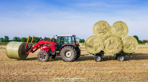 tractor moving round bales of hay